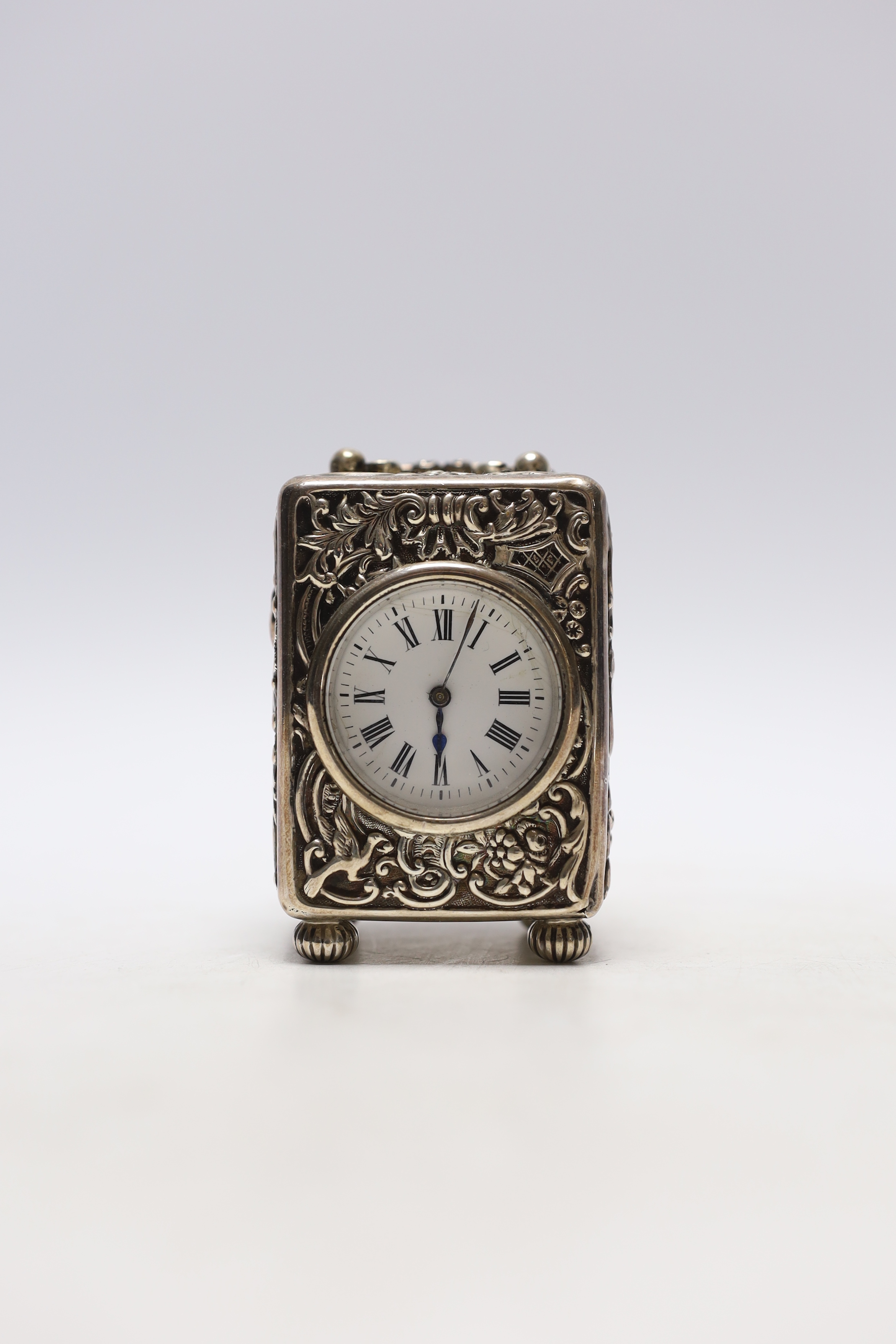 A late Victorian repousse silver cased carriage timepiece, by William Comyns, London, 1899, with Roman dial and key, height 8cm.